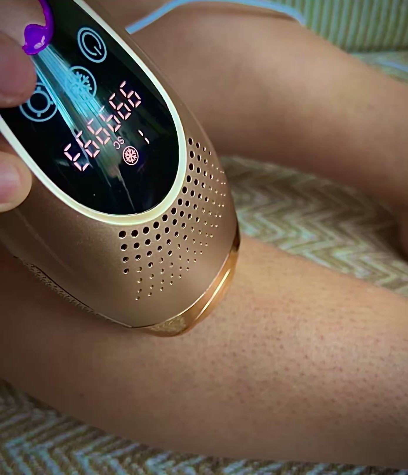 Charger la vidéo : Vidéo de démonstration de 8 secondes montrant une femme utilisant l'épilateur à lumière pulsée Lumizia Confort sur sa jambe, confortablement installée sur un canapé.